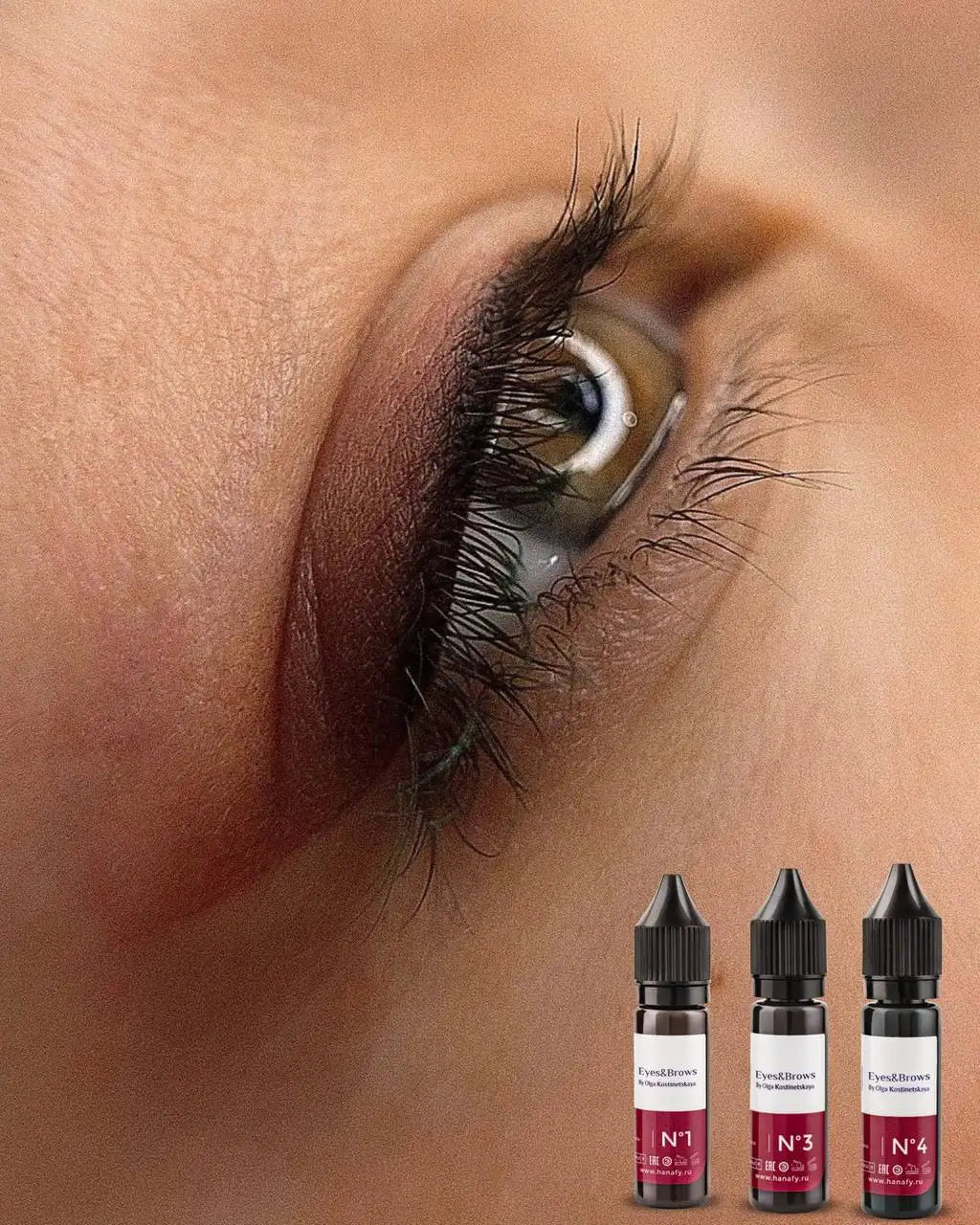 Close-up of an eye with long lashes and four small bottles with labels on a blurred background hanafy eyes and brows pigments eyeliner 