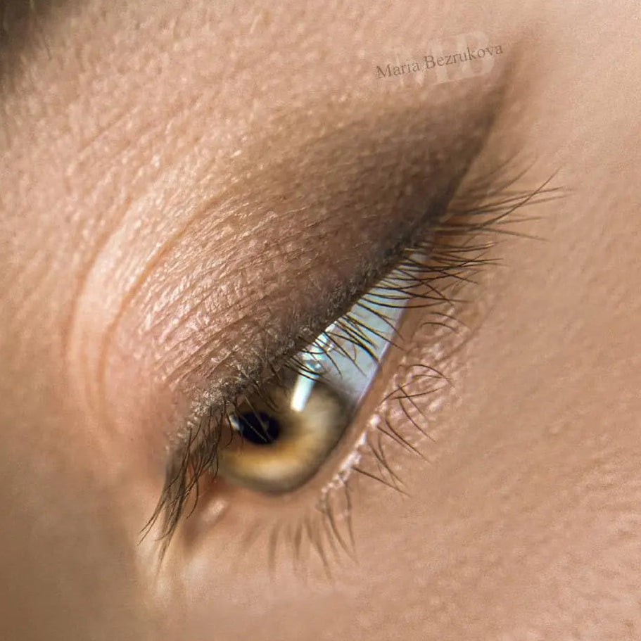 Close-up of an eye with eyeliner from hanafy permanent makeup on a beige background.